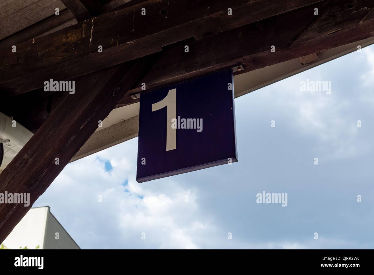 Platform 1 sign at a train station. White number one on a blue metal