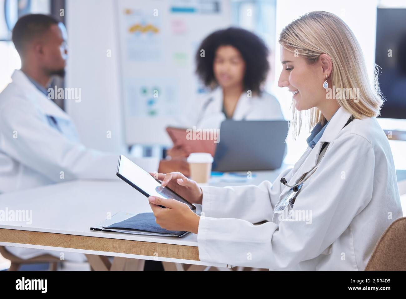 Teamwork, innovation and doctors working on digital tablet in a meeting or conference, reading and research together. Health care workers Stock Photo