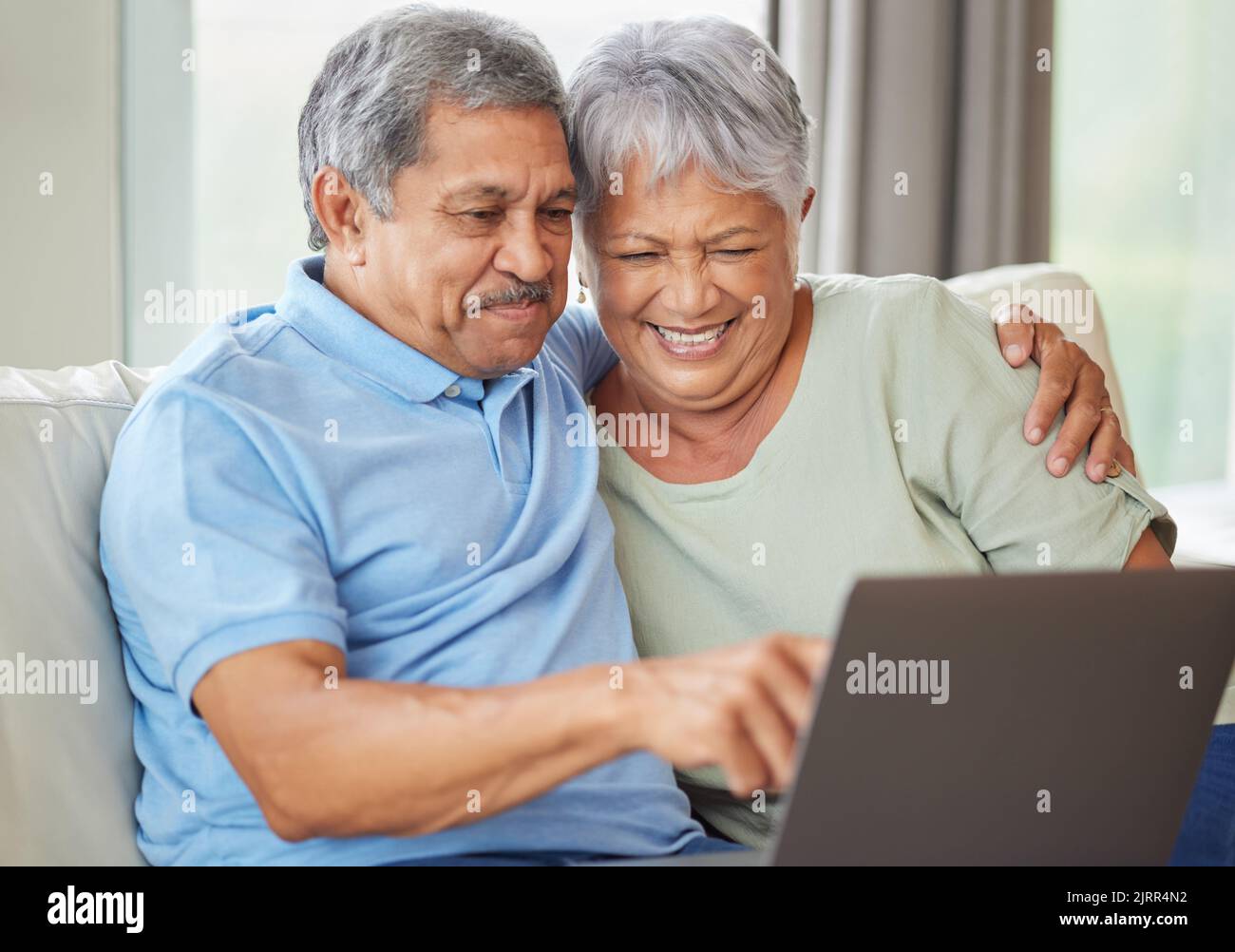 Elderly couple laptop on video call, social media or internet on their laptop on living room sofa. Relax senior man and woman watching or reading news Stock Photo