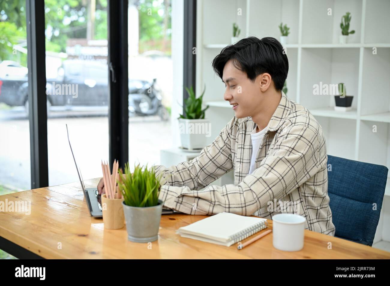 A handsome young Asian man in the coffee shop co-working space, using ...