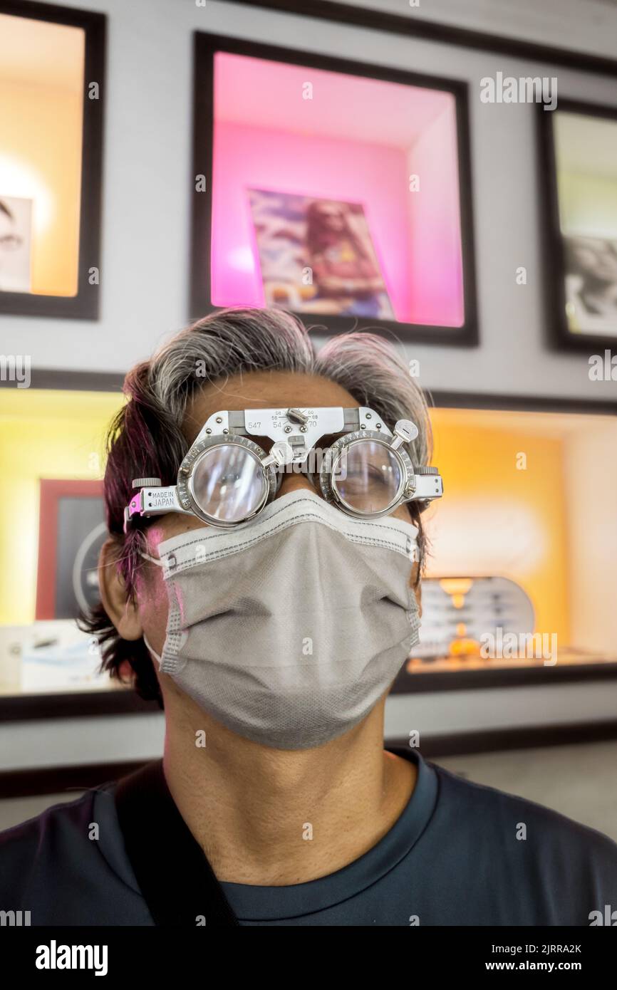 Mature Southeast Asian man wearing eyeglasses for vision correction at eyeglasses store Stock Photo