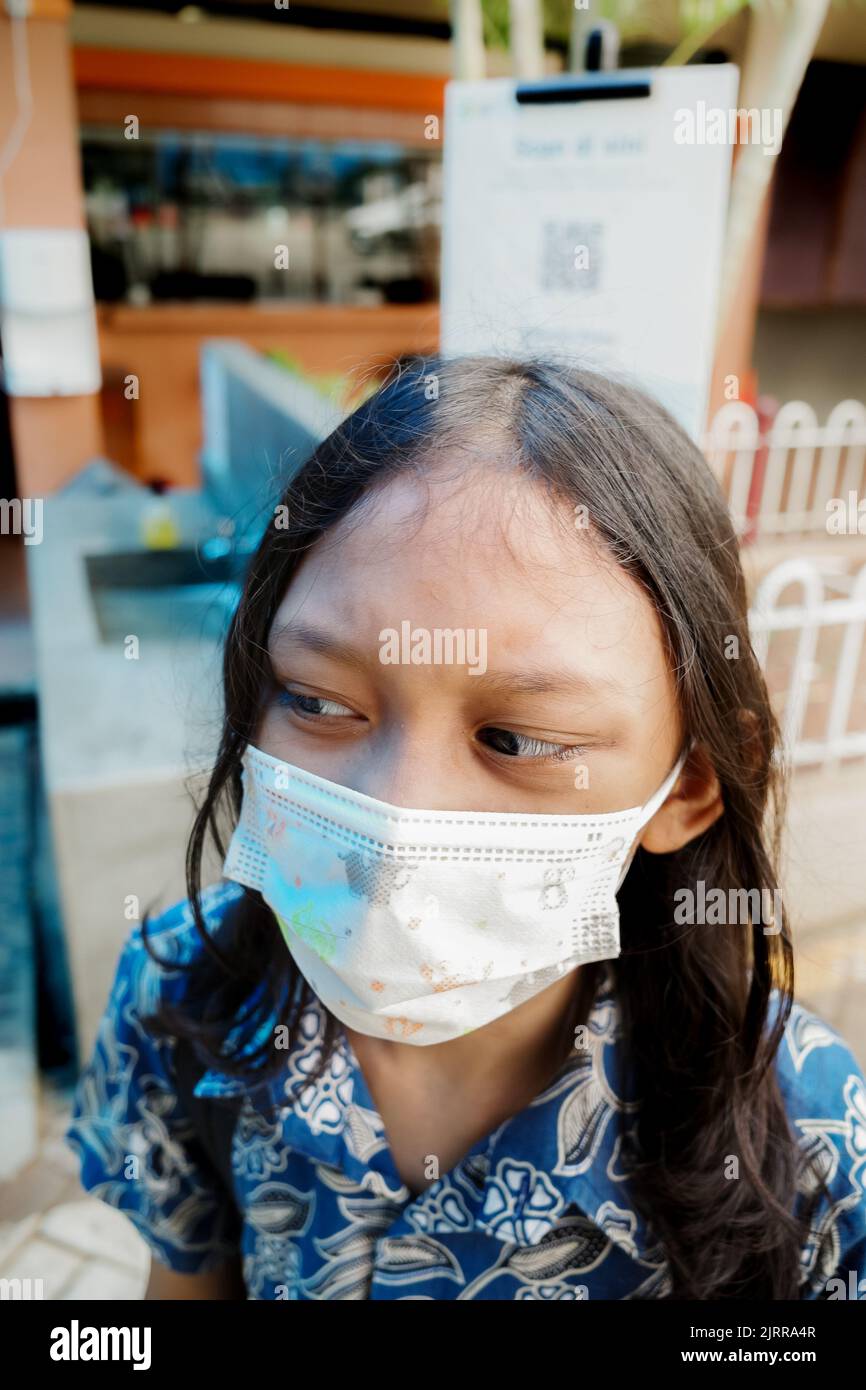 Southeast Asian elementary schoolgirl wearing face mask back to school again after covid pandemic Stock Photo