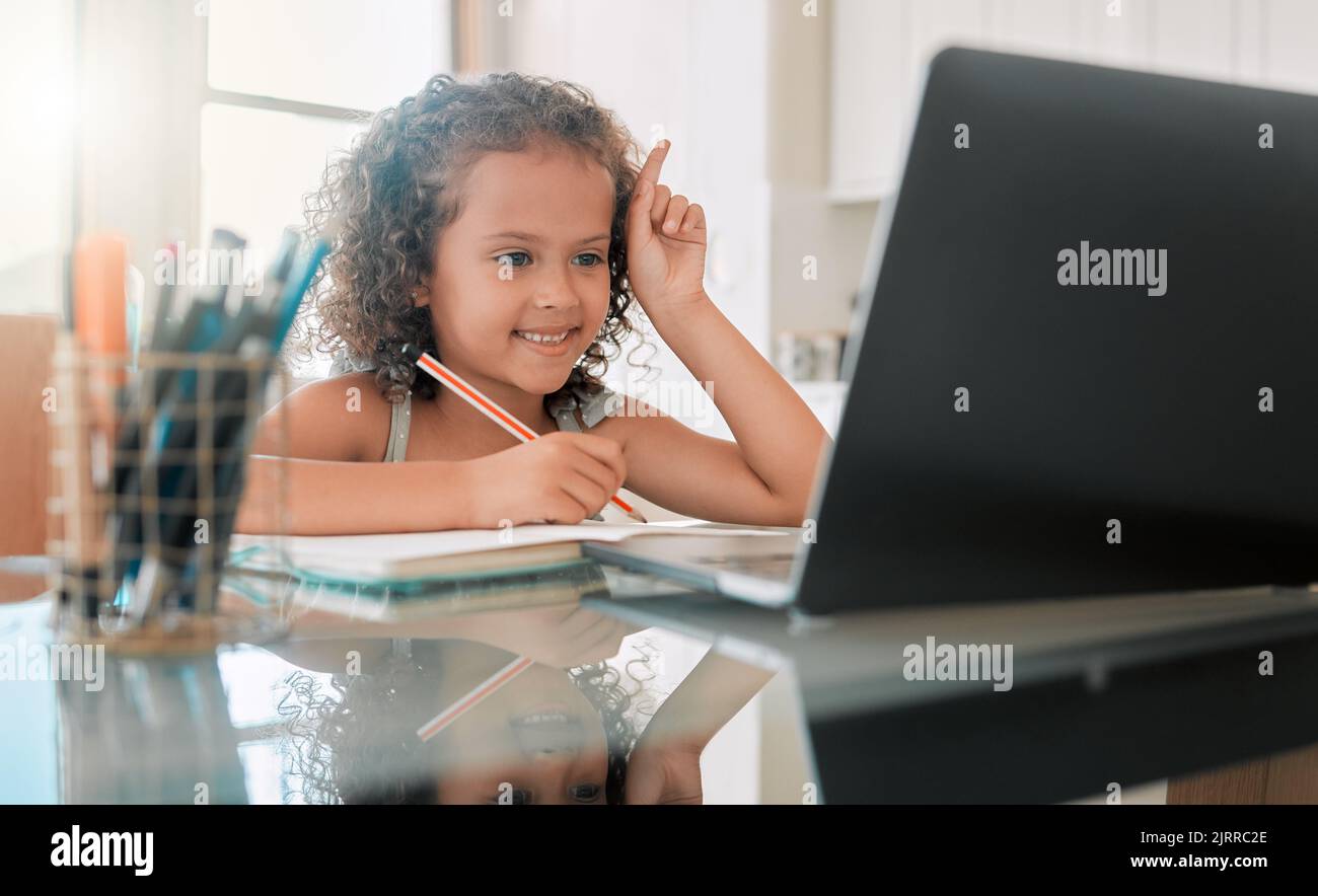 School, learning and lesson for a little girl e-learning or online homeschooling using home internet and a laptop. An intelligent young child doing Stock Photo