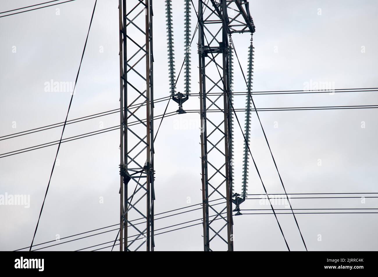 Electric power lines divided by safe guard insulating frame transfening safely high voltage electrical energy through cable wires. Electricity Stock Photo