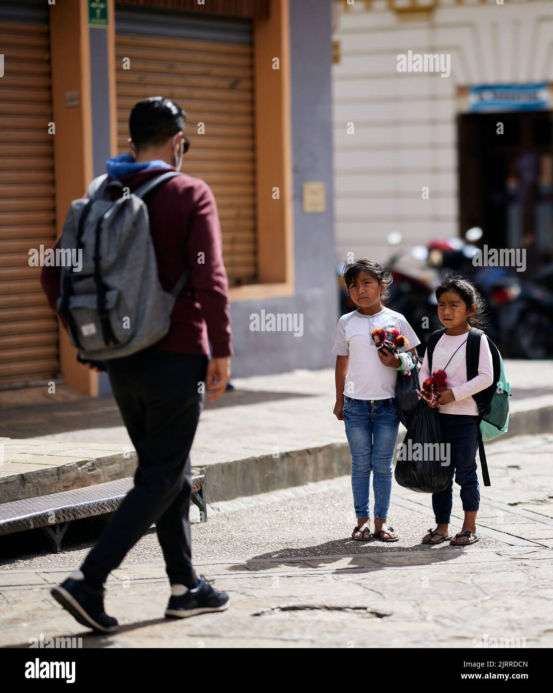 Two girls selling handmade crafts to a male tourist during the pandemic in San Cristobal, Mexico Stock Photo
