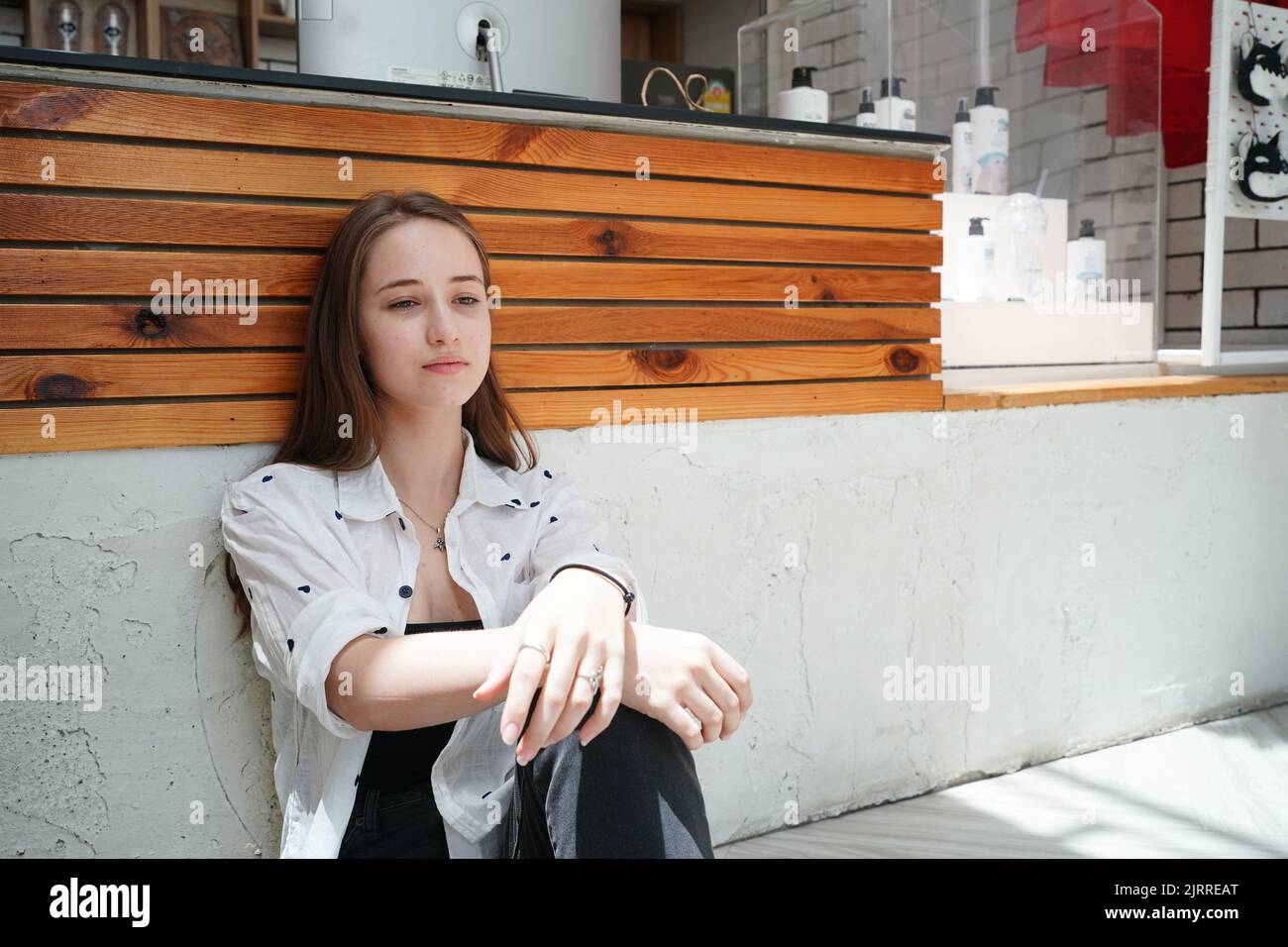 Cute blonde girl sitting on floor in cafe and looking away Stock Photo ...