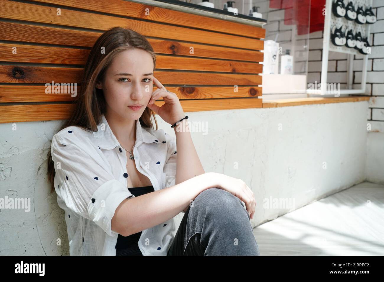 Cute blonde girl sitting on floor in cafe and looking away Stock Photo ...