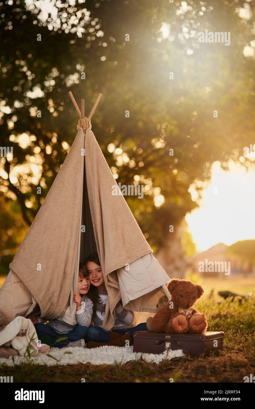 We see you. Portrait of two cute little siblings playing together in a teepee outside. Stock Photo