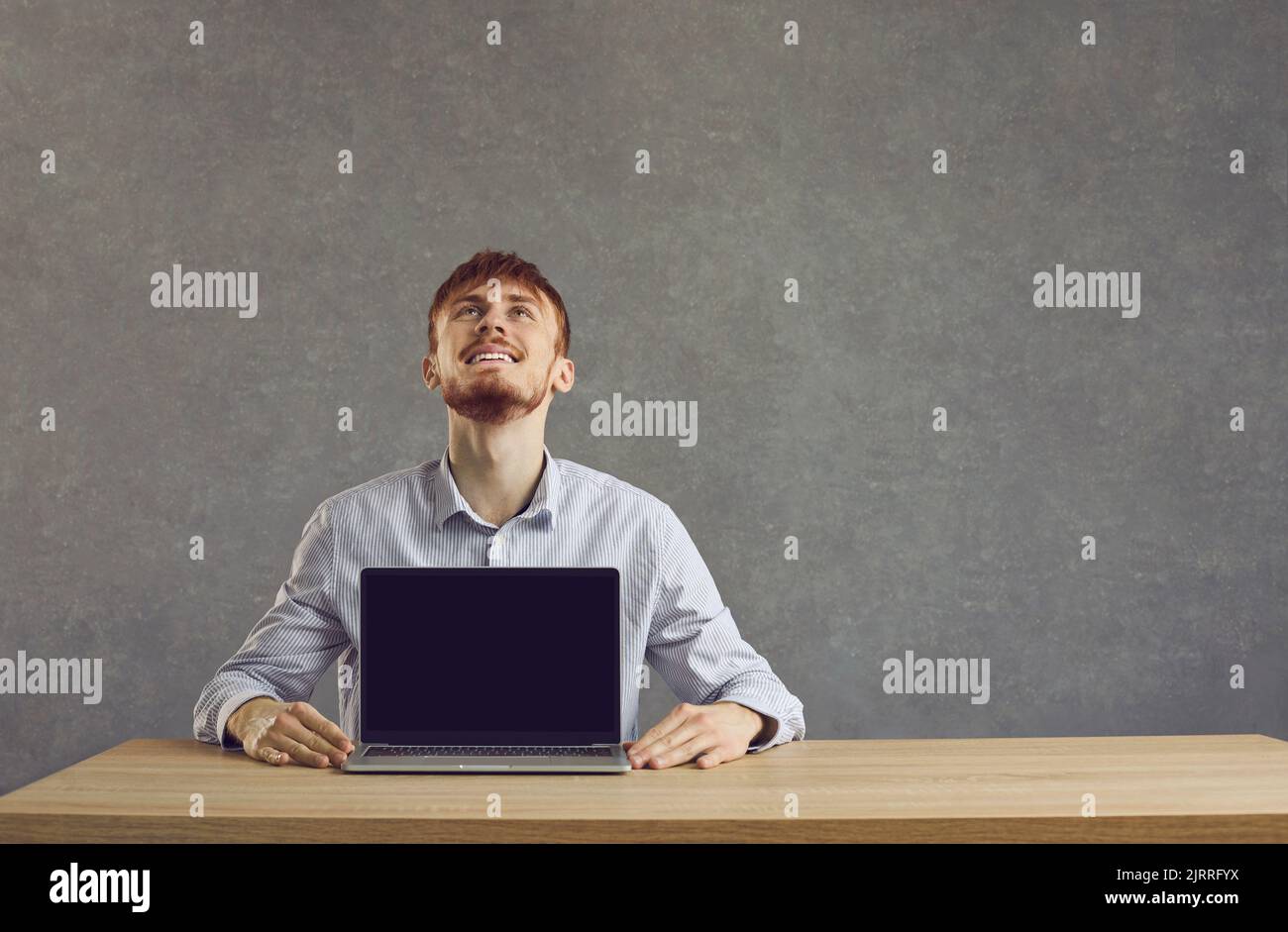 European cheerful man shows a laptop with a black screen on the table Stock Photo