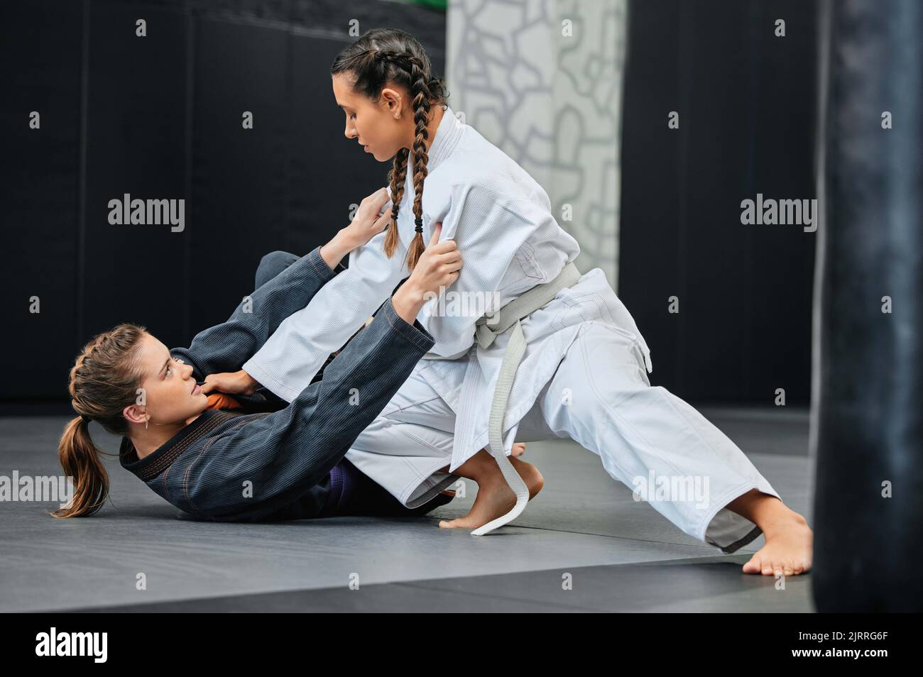 Mma, karate and jiu jitsu with two female athletes practicing, training and sparring in fight class. Healthy, fit and active women in gi or uniform Stock Photo