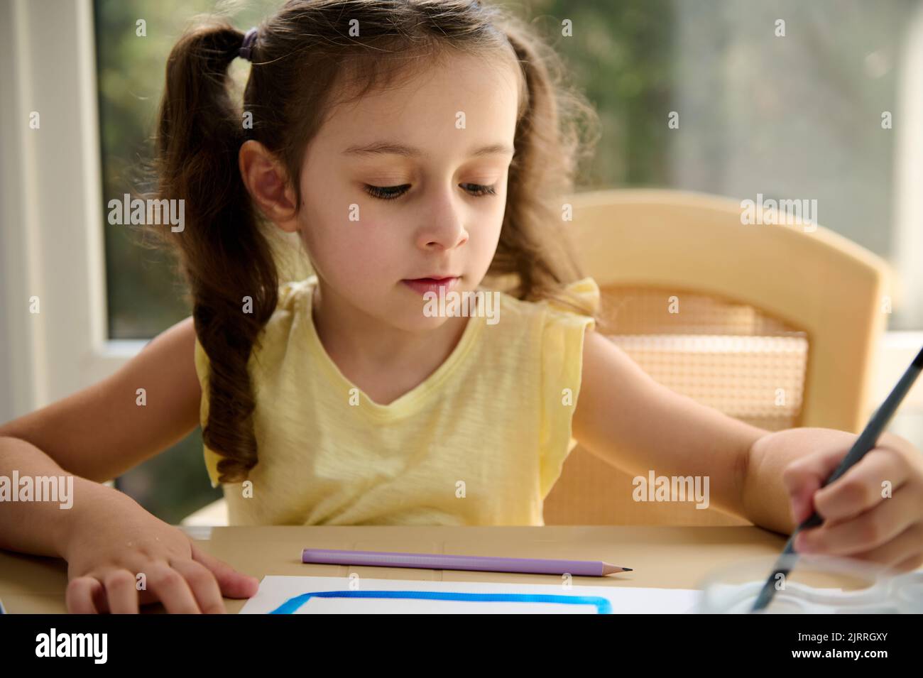 Closeup portrait of little girl painting with watercolor paints during