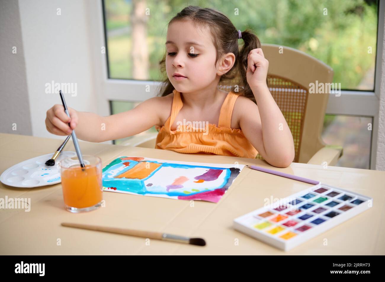 Adorable Caucasian little girl enjoys watercolor painting at home ...