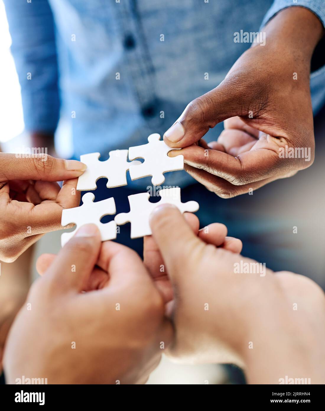Pulling together to solve a problem. a work group connecting pieces of a puzzle. Stock Photo
