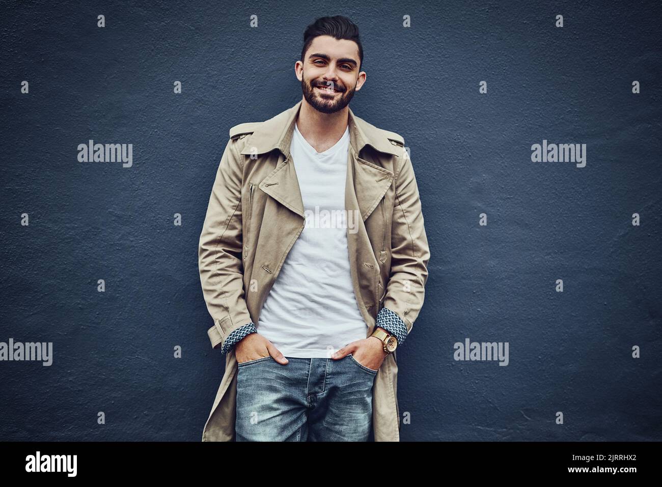 Streetwear - understated yet stylish. Portrait of a fashionable young man wearing urban wear and posing against a gray wall. Stock Photo