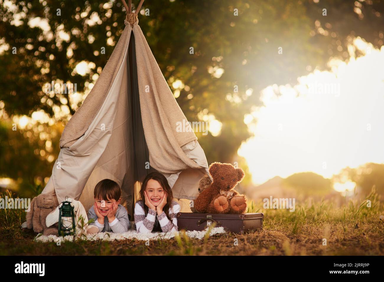 Well let you come in if you know the password. Portrait of two cute little siblings playing together in a teepee outside. Stock Photo