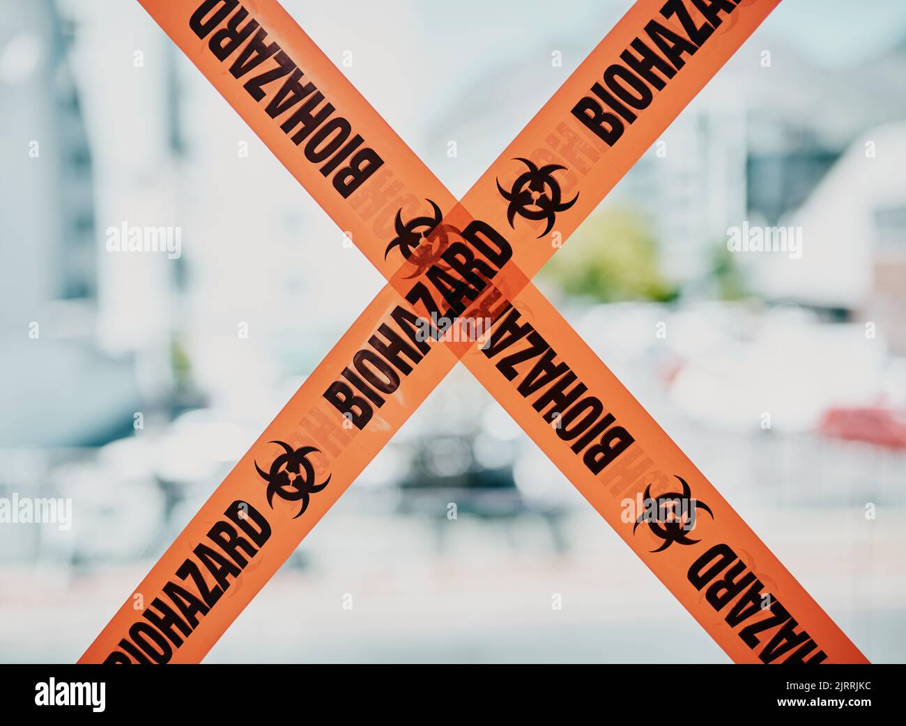 Biohazard caution, danger barrier tape of a quarantine zone. Bright orange safety stripes across infected area, no entry or cross, room closed down Stock Photo