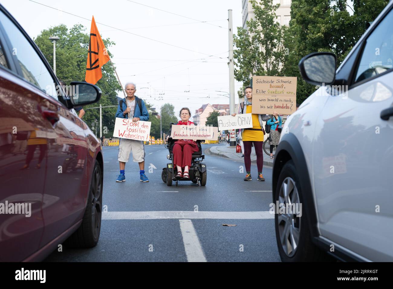 Dresden, Germany. 26th Aug, 2022. Environmental activists stand with their banners in front of stationary cars during a demonstration on the roadway at a traffic light intersection at Albertplatz. Credit: Sebastian Kahnert/dpa/Alamy Live News Stock Photo