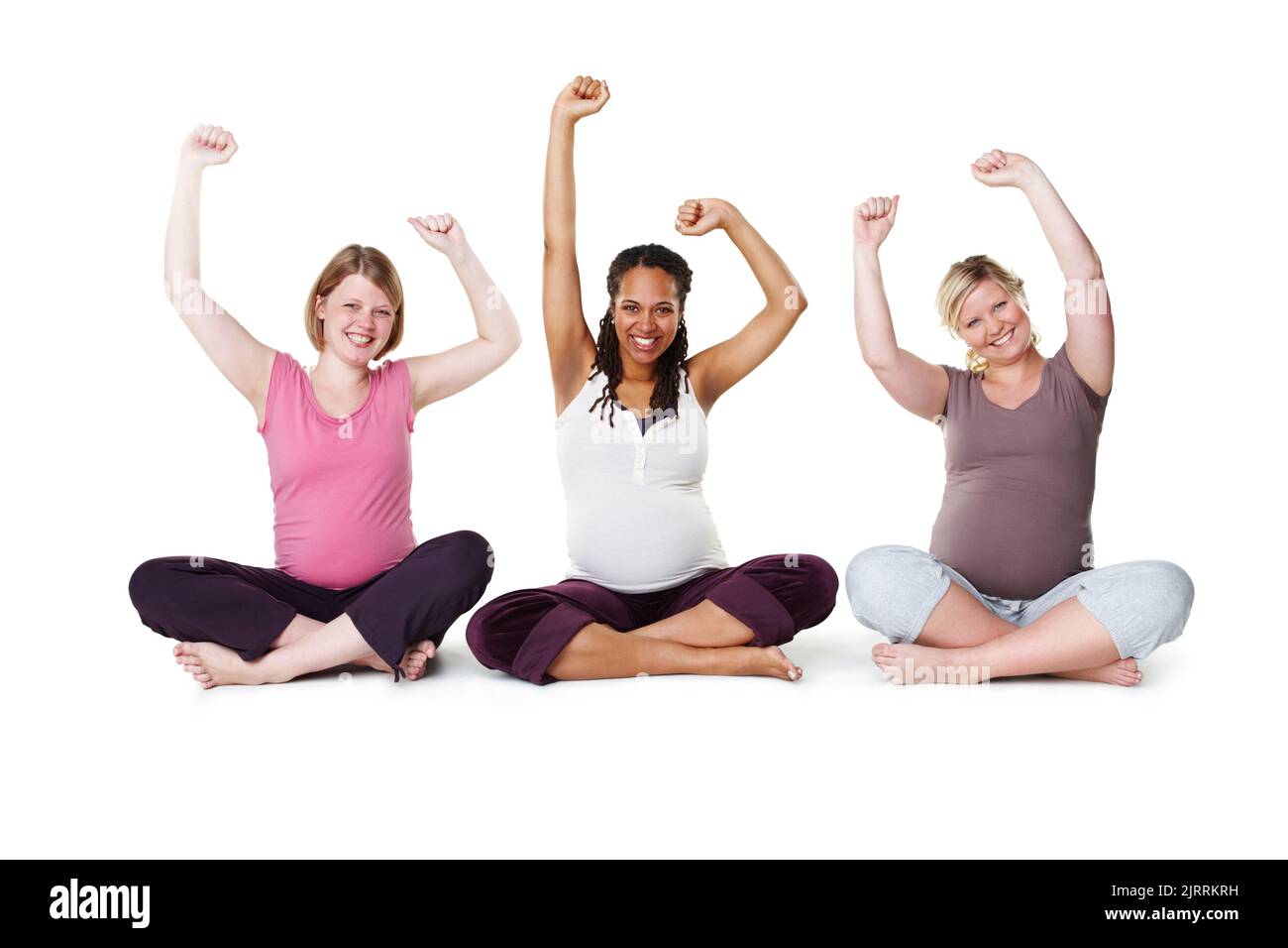 Pregnant, happy, and healthy, women sitting on the floor, arms raised