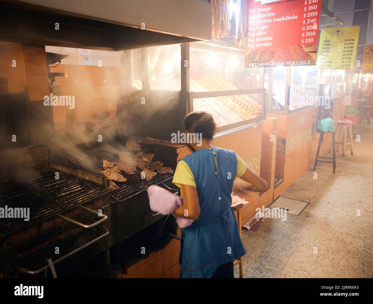 A woman working at the grilling station in a food market in Oaxaca, Mexico Stock Photo