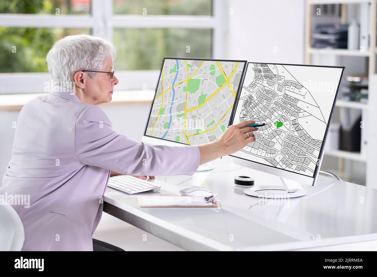 Businessperson Analyzing Cadastre Map On Computer In The Office Stock Photo