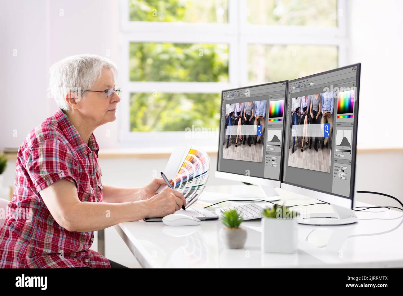 Website Graphic Designer Working In Office On Multiple Screens Stock Photo