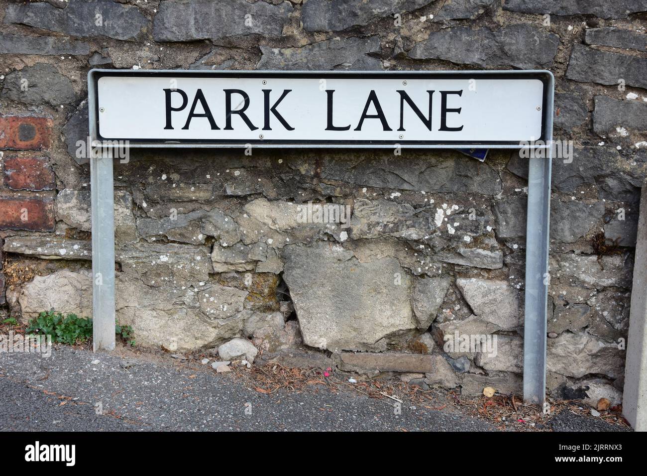 A street name sign for Park Lane mounted in front of a stone wall Stock Photo