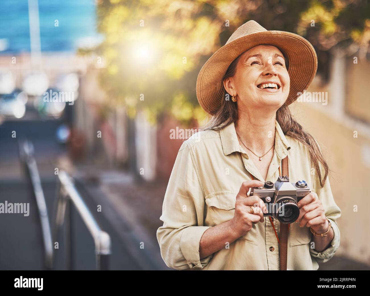 Happy photographer tourist taking photo of historic building with camera, smiling and carefree. Excited mature female solo travel journey, enjoying Stock Photo