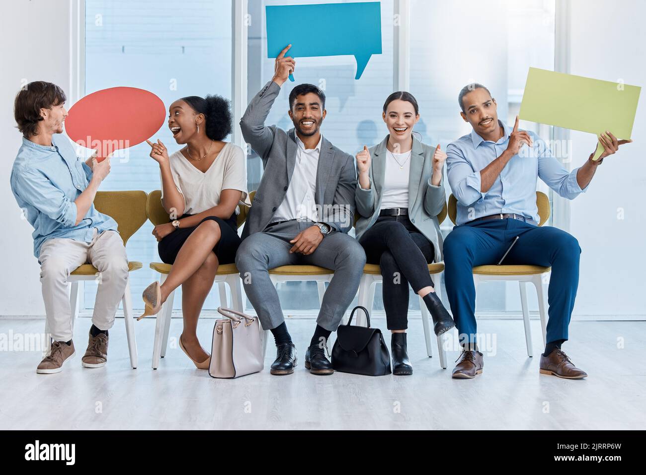 Speech bubbles, voice and vote by business people happy and sitting in an office. A diverse team of employees holding empty comment signs or icons for Stock Photo