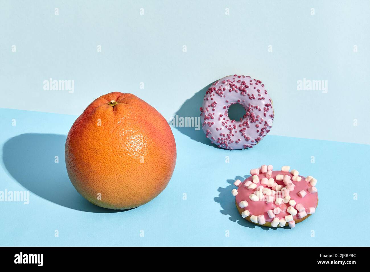 Composition of fresh fruits and sweets, two donuts and juicy grapefruit