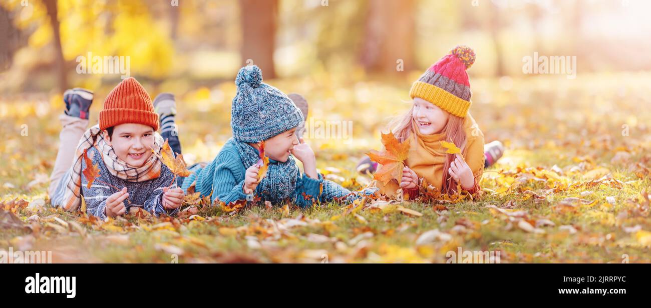 Group of children lying onthe ground in autumnal park Stock Photo