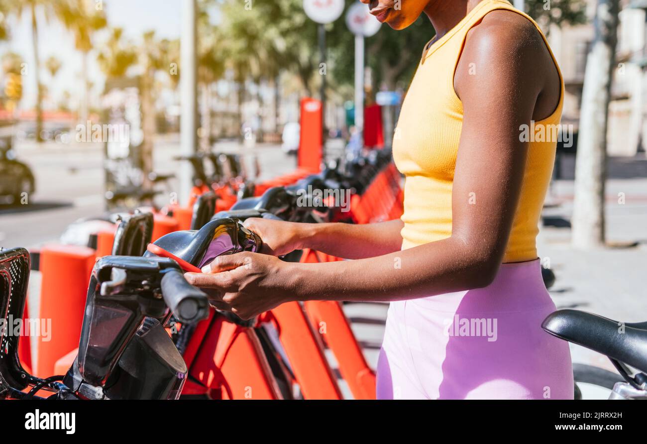 unrecognizable african woman using her phone to use public system of bicycle renting Stock Photo