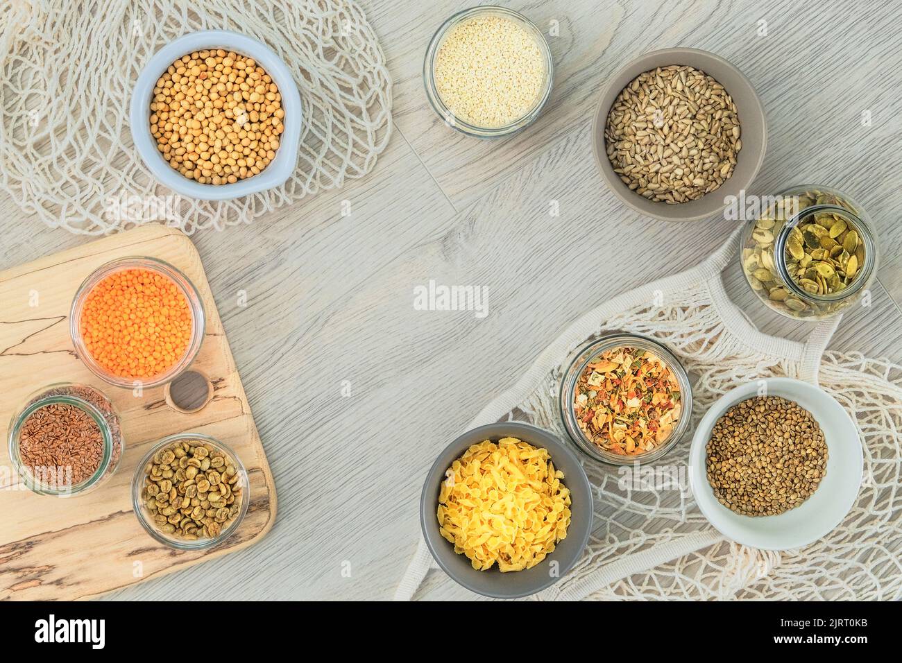 Set of vegetarian organic products in glass jars and bowls on a white wooden background. Top view, copy space. Stock Photo