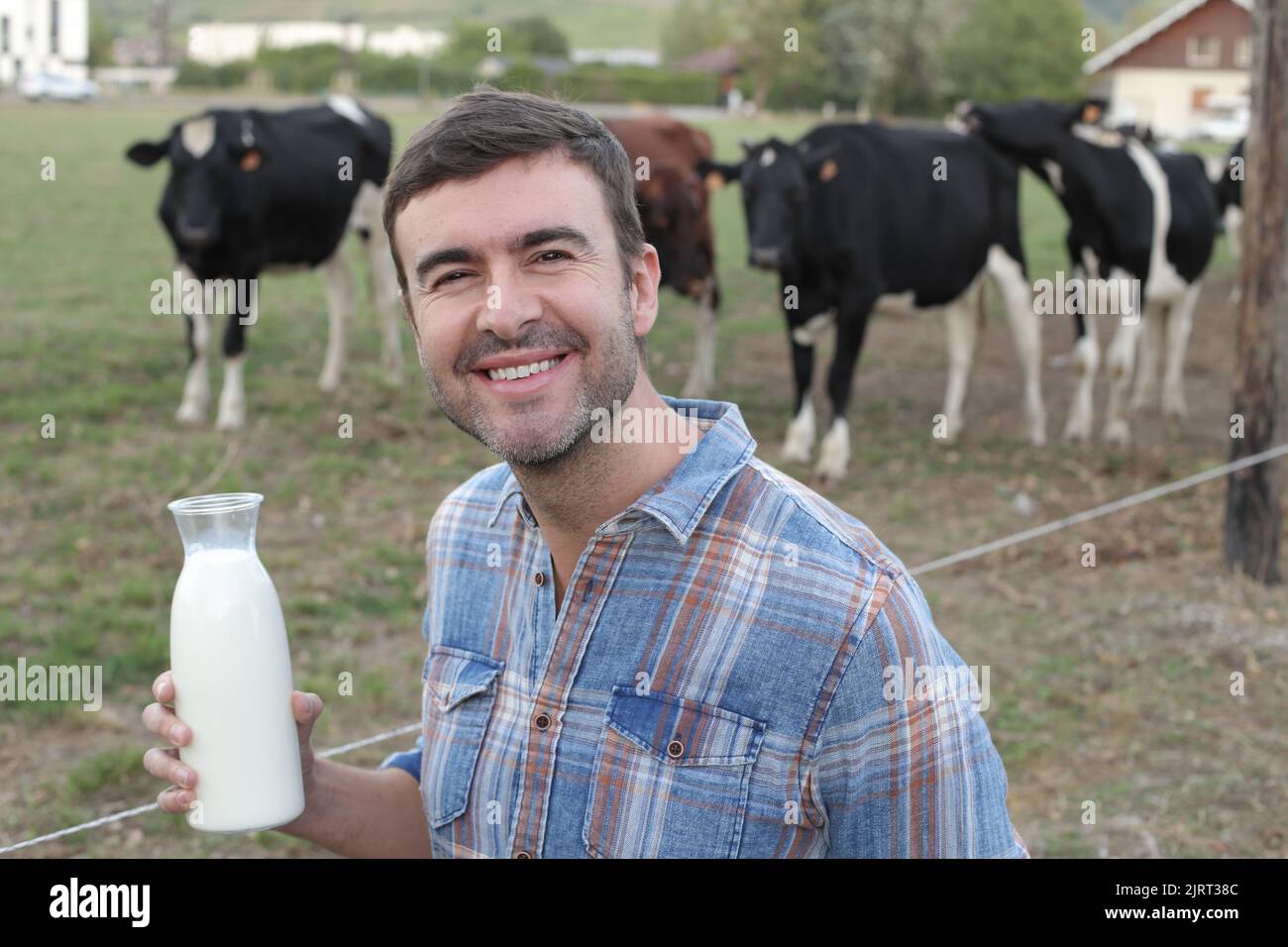 Farmer holding fresh milk with cows in the background Stock Photo - Alamy