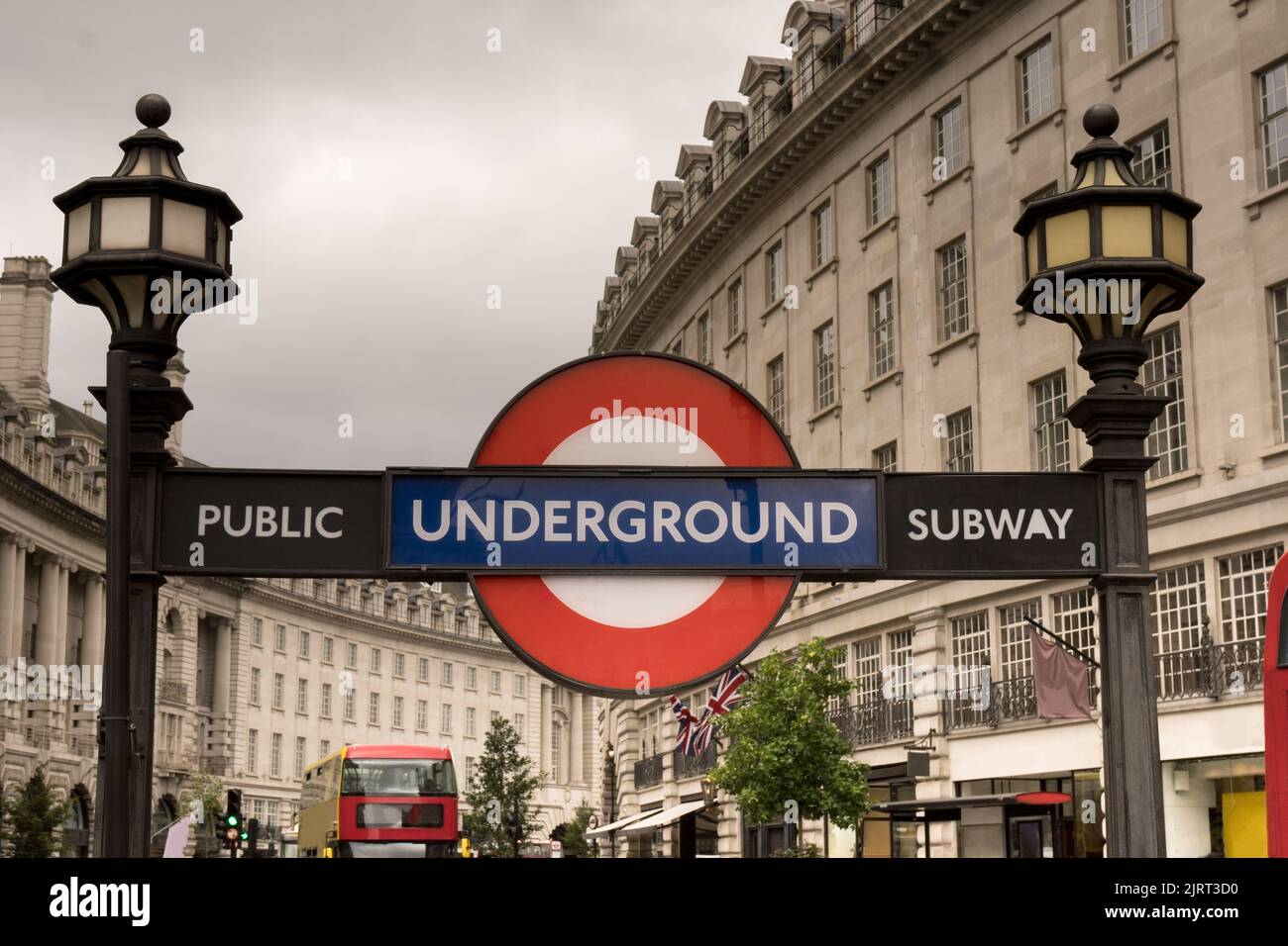 editorial red blue underground metro subway sign at piccadilly circus with historic buildings in the background against cloudy white sky concept for L Stock Photo