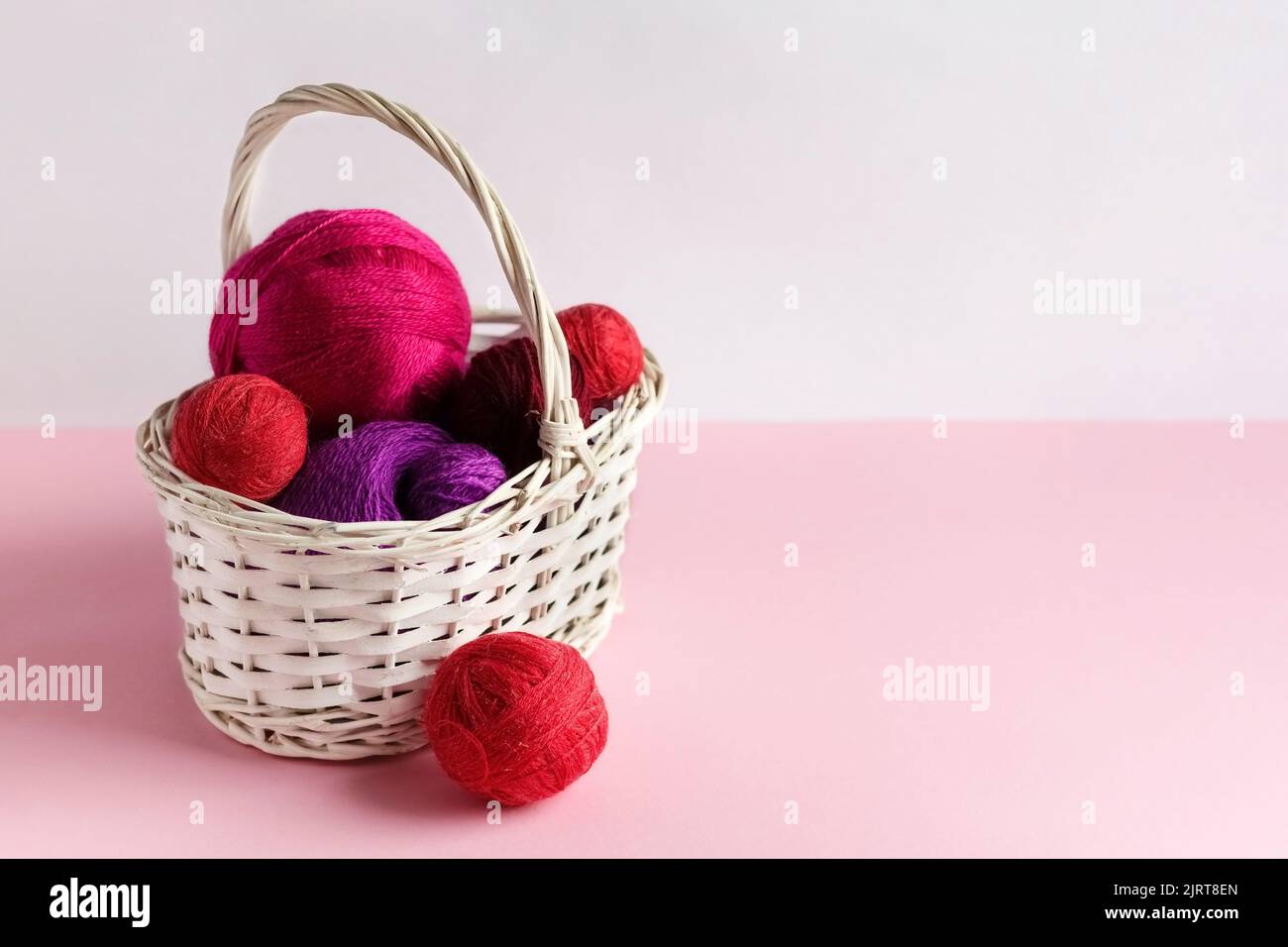 Pink and red balls of thread in a basket on a pink background, Hobby Stock Photo