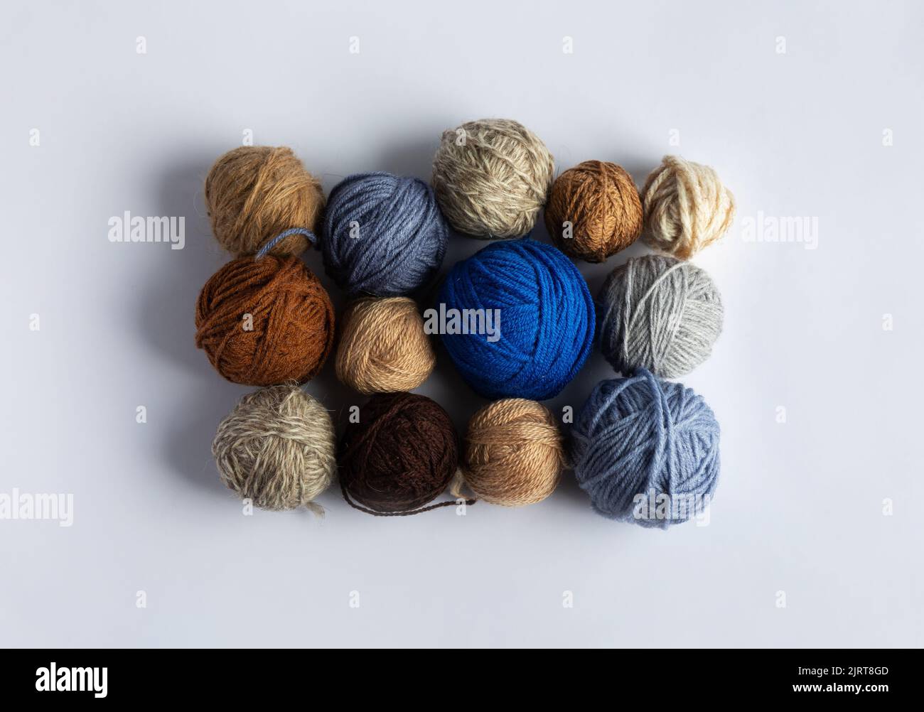 Blue, gray and brown balls of knitting thread on a blue background for hobbies. Flat lay Stock Photo