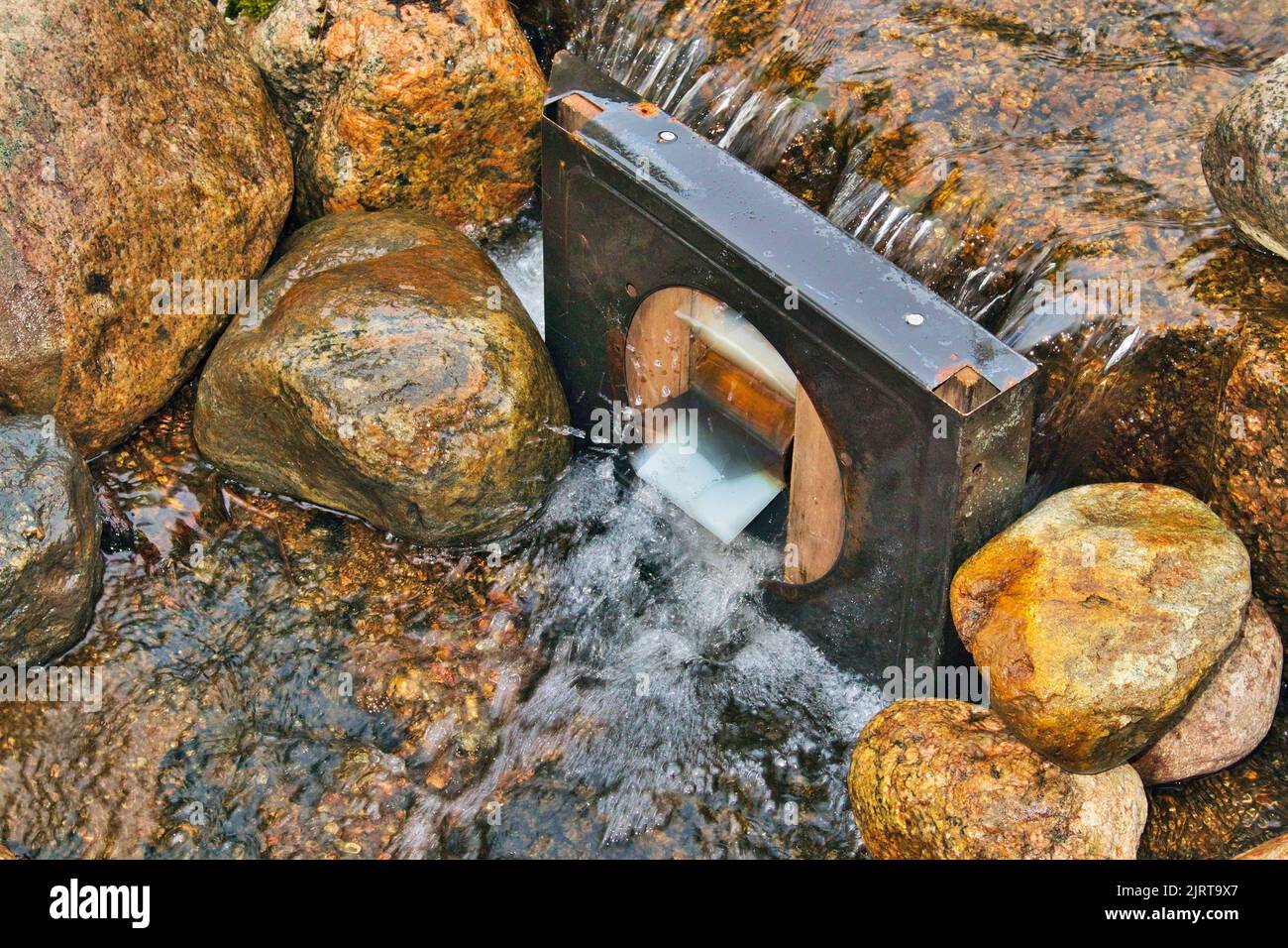 Small metallic water wheel in the stream Stock Photo