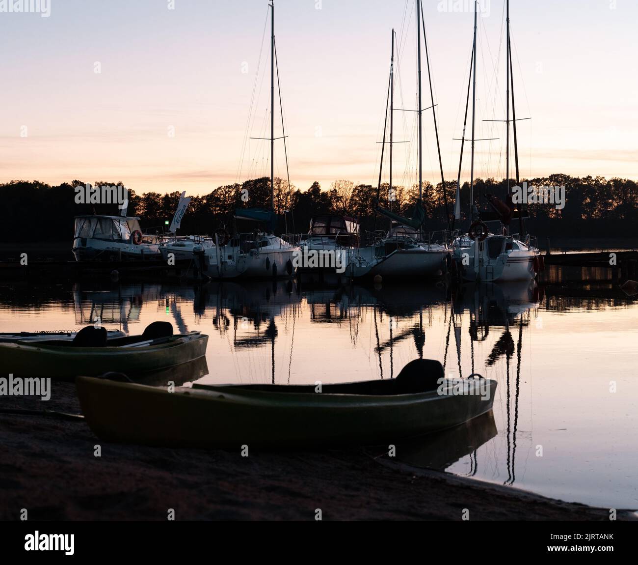 The sky and boats reflected on the water with trees in the background ...