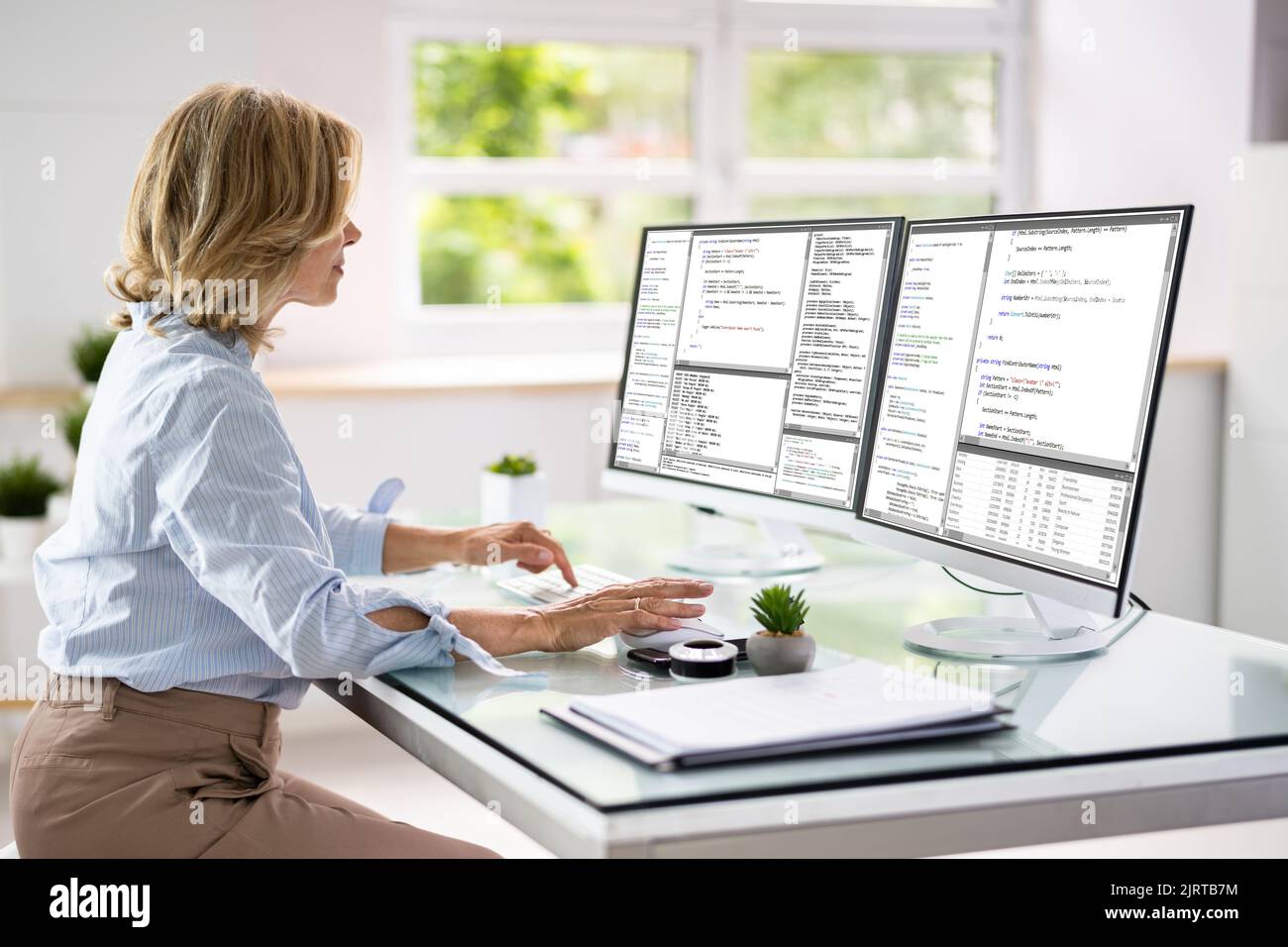 Programmer Woman Coding On Multiple Computer Screens Stock Photo - Alamy
