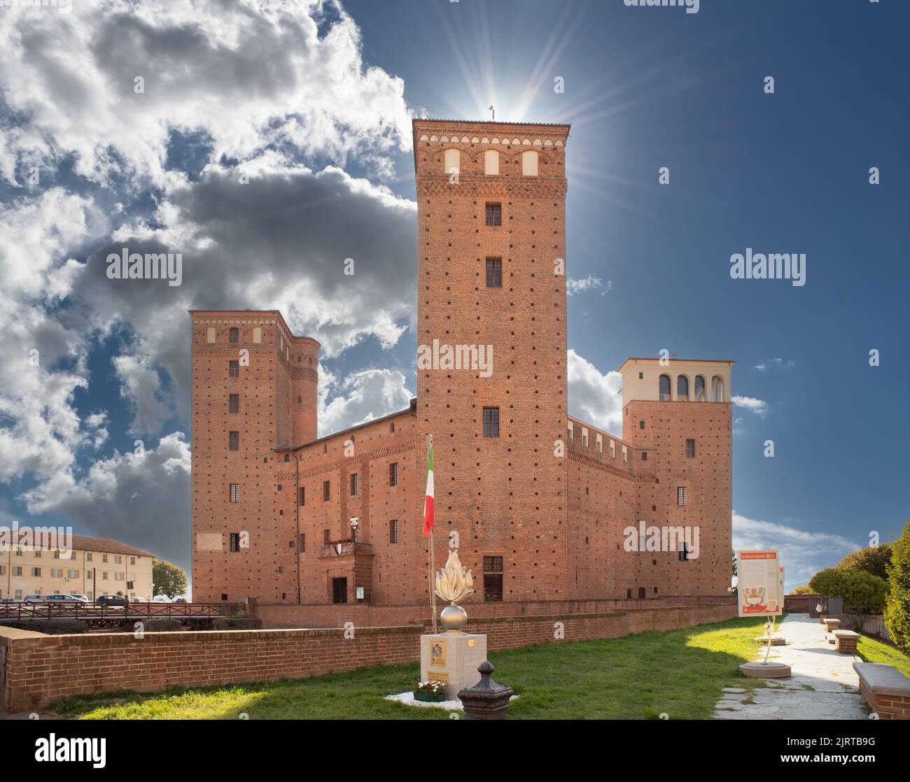 Fossano, Cuneo, Italy - August 25, 2022: The castle of the Princes of Acaja (XIV century) in piazza Castello on blue cloudy sky with sun rays Stock Photo