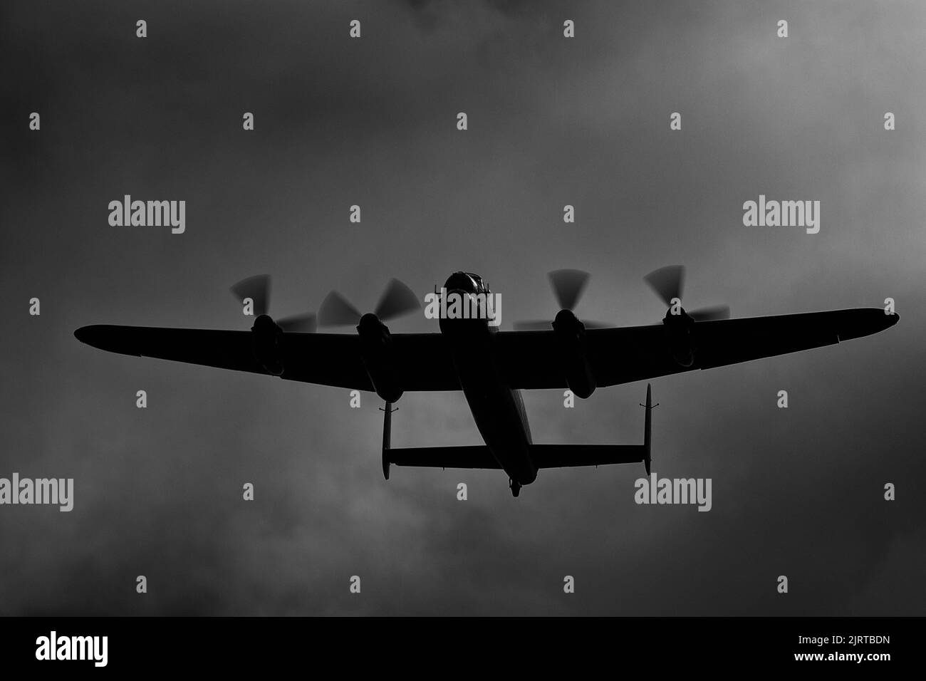 An Avro Lancaster flies overhead under a stormy sky Stock Photo