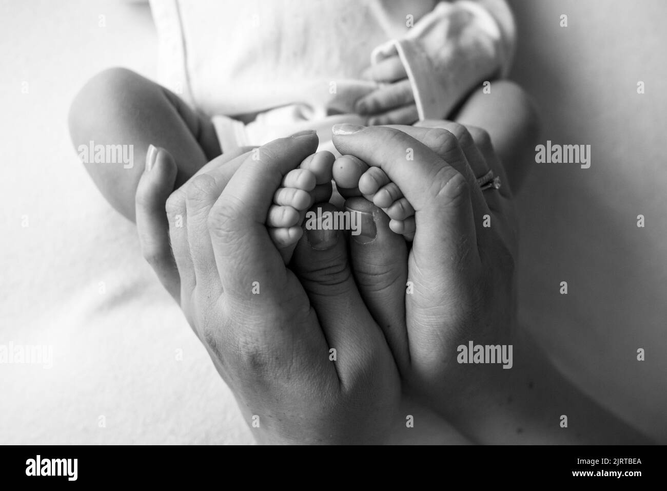 Hands of parents. The legs, feet of the newborn in the hands of mom and ...