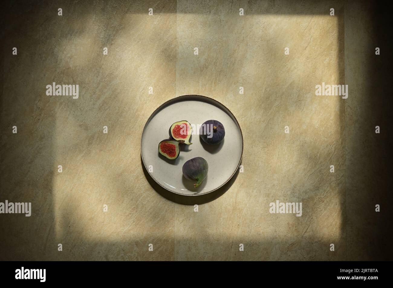 Abstract Figs fruits placed on a plate on a table with a natural frame from sun Stock Photo