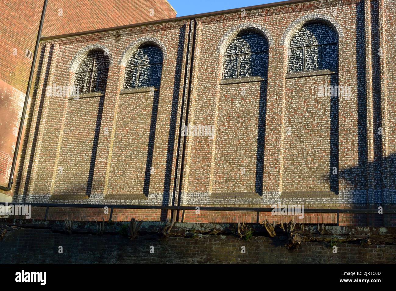 Victorian warehouse in Norwich, Norfolk, seen from the River Wensum. The walls are painted with the words of Sir Thomas More's book 'Utopia' Stock Photo