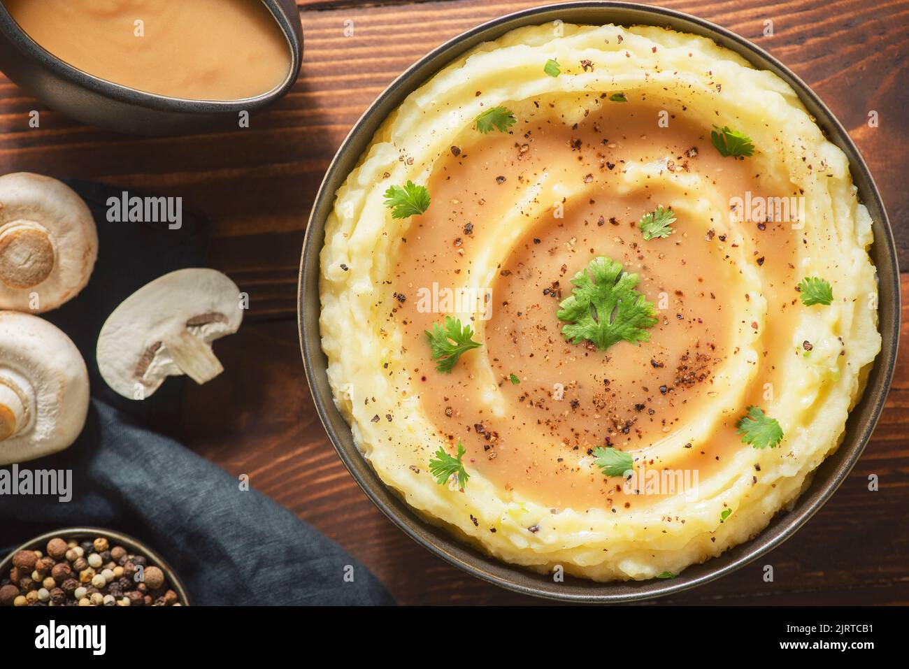 Delicious perfect mashed potatoes with mushroom, tasty creamy gravy and fresh herbs . top view with close up. Stock Photo