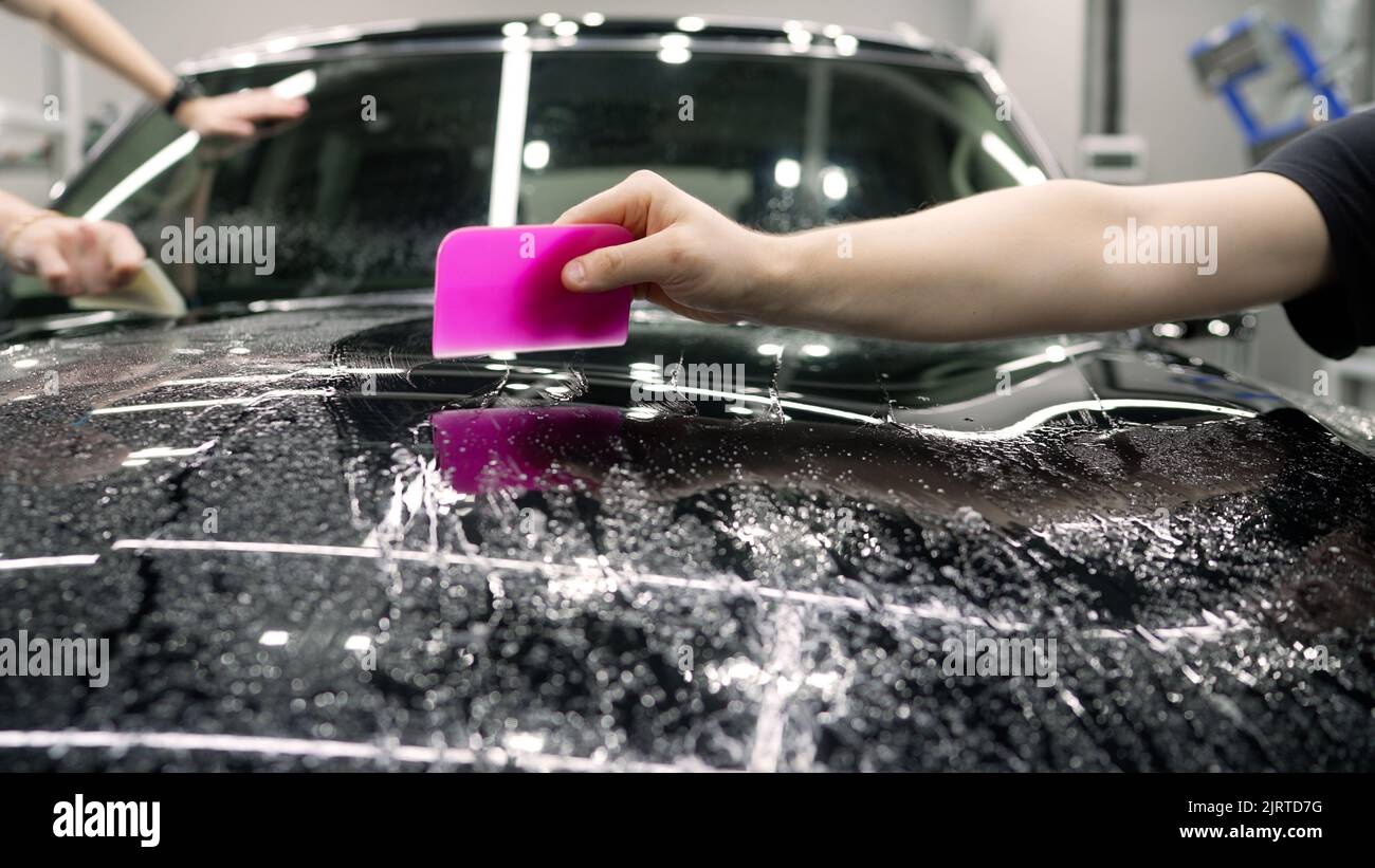 Applying a protective film. Smoothing the protective film on the car