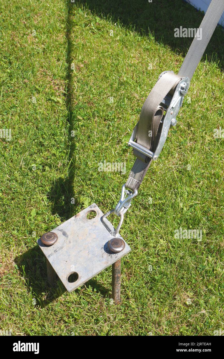 Marquee tent stake with ratchet strap and base plate Stock Photo - Alamy
