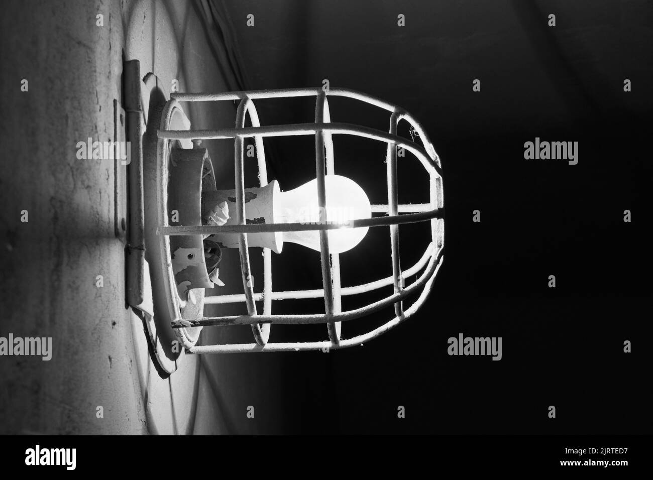 Glowing incandescent lamp. Old electric light bulb with a metal grate