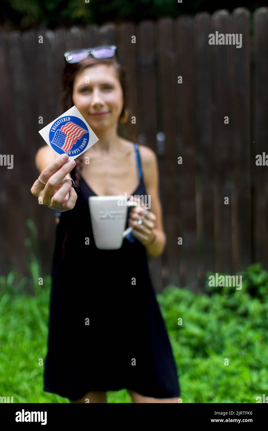 A young woman holds a voter registration sticker, as the Supreme Court's Dobbs decision creates a surge of newly registered voters across the US Stock Photo