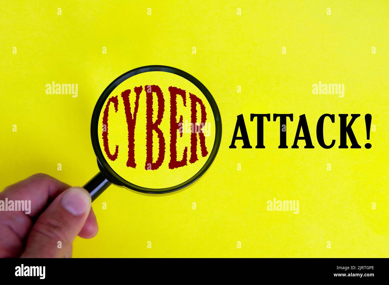 Cyber attack text on yellow cover with hand holding magnifying glass. Internet security concept. Stock Photo